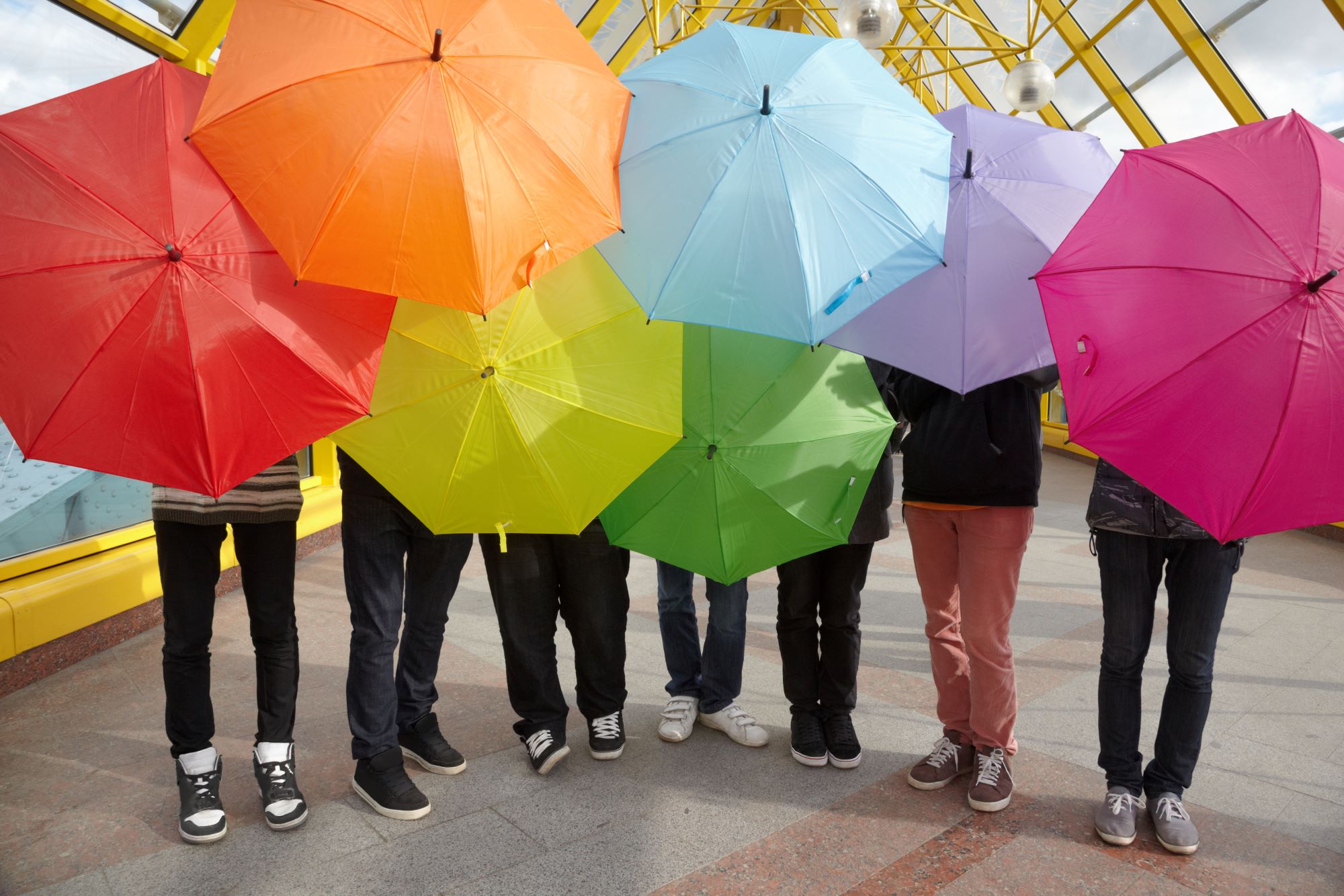 Bunter Regenschirme werden von mehreren Menschen hochgehalten